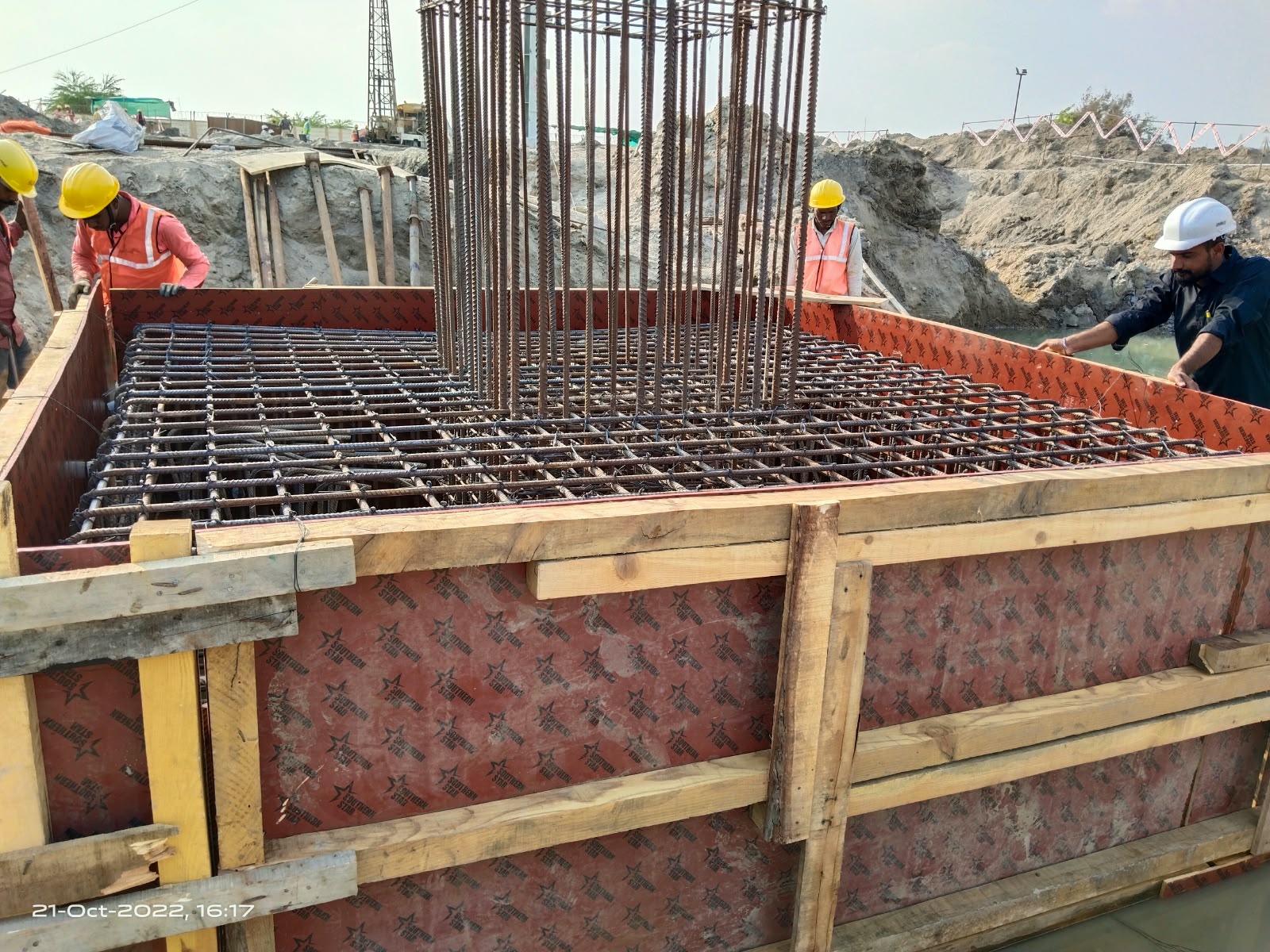 Workers around a raft foundation cage inside timber and plywood formwork