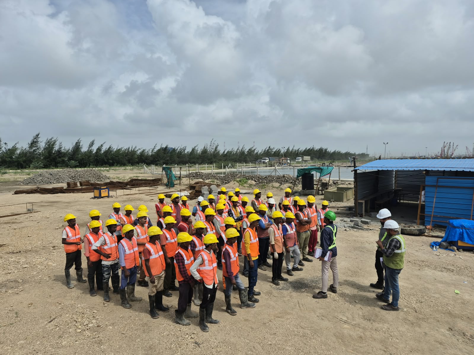 A group of workers in helmets and high-visibility vests gathered for a site briefing